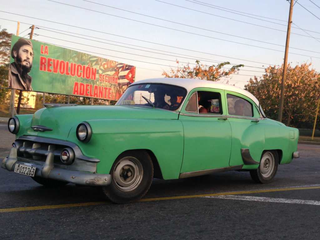 This is a máquina, or Cuban collective taxi. The billboard behind it reads: The Revolution Will Continue Forward