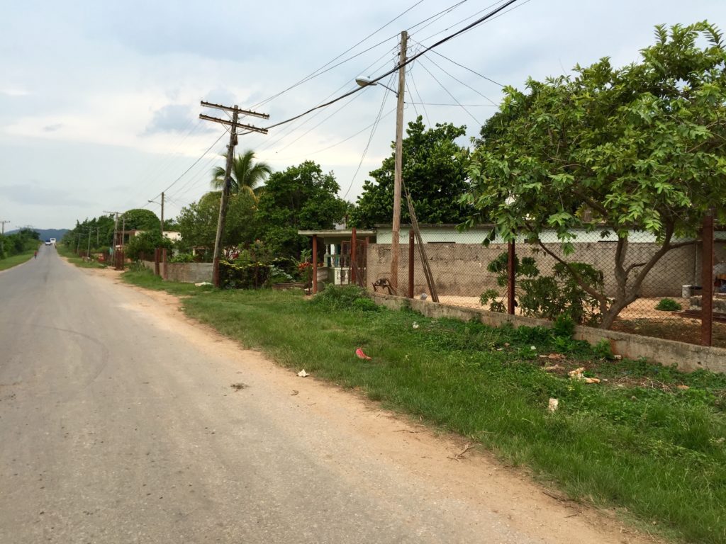A road with power lines and small homes built along one side
