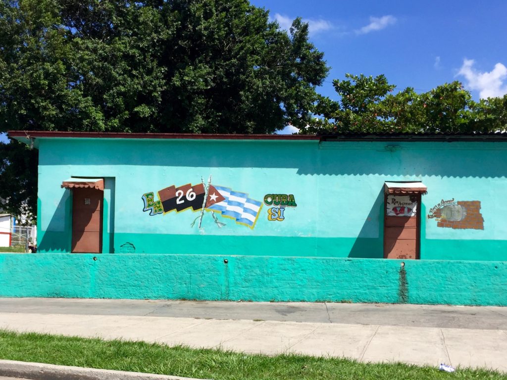 A building is painted with a Cuban flag and patriotic slogans.