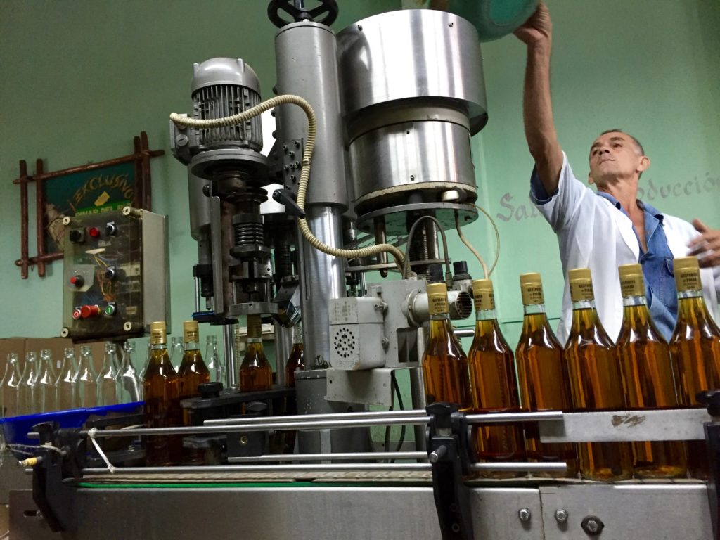 A man reaches up to adjust a bottling machine