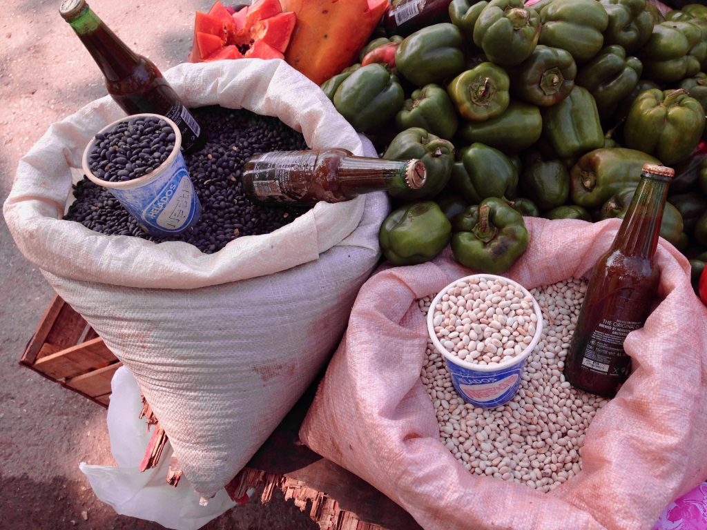 Sacks of beans next to a pile of bell peppers