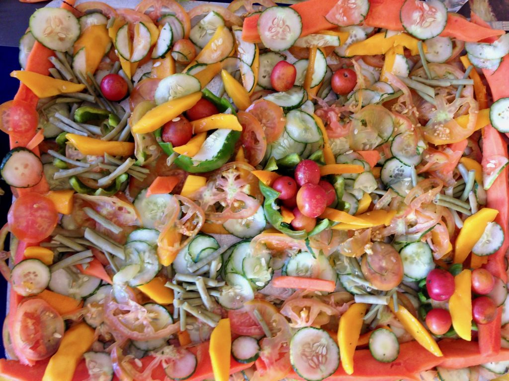 A salad tray of colorful vegetables and mango