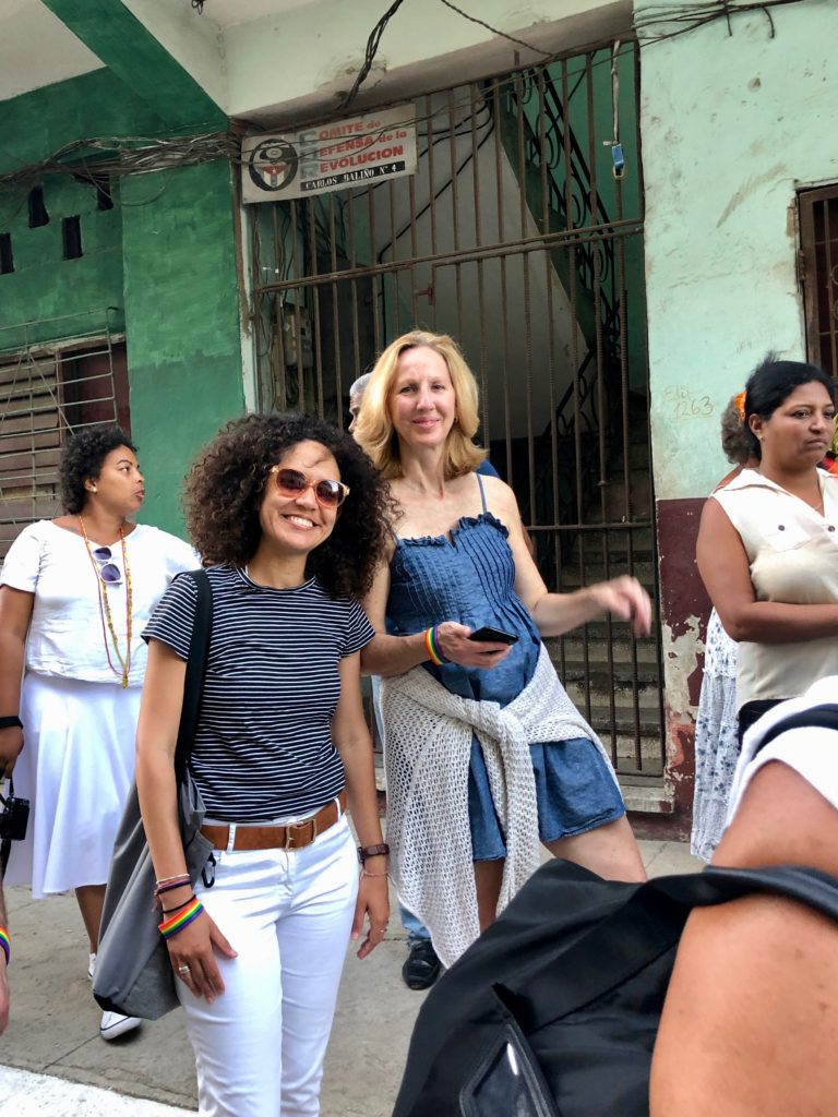 Two women stand in the street and smile for the camera