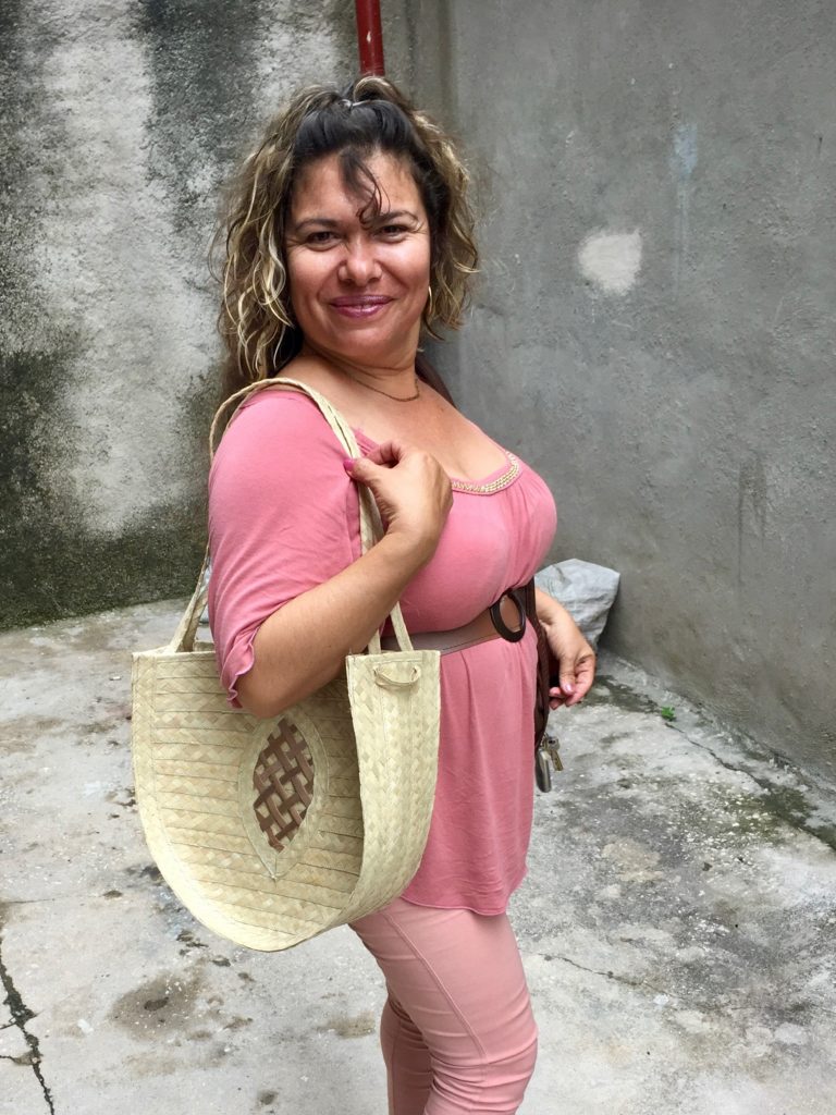 A woman stands looking at the camera with a large purse over her shoulder