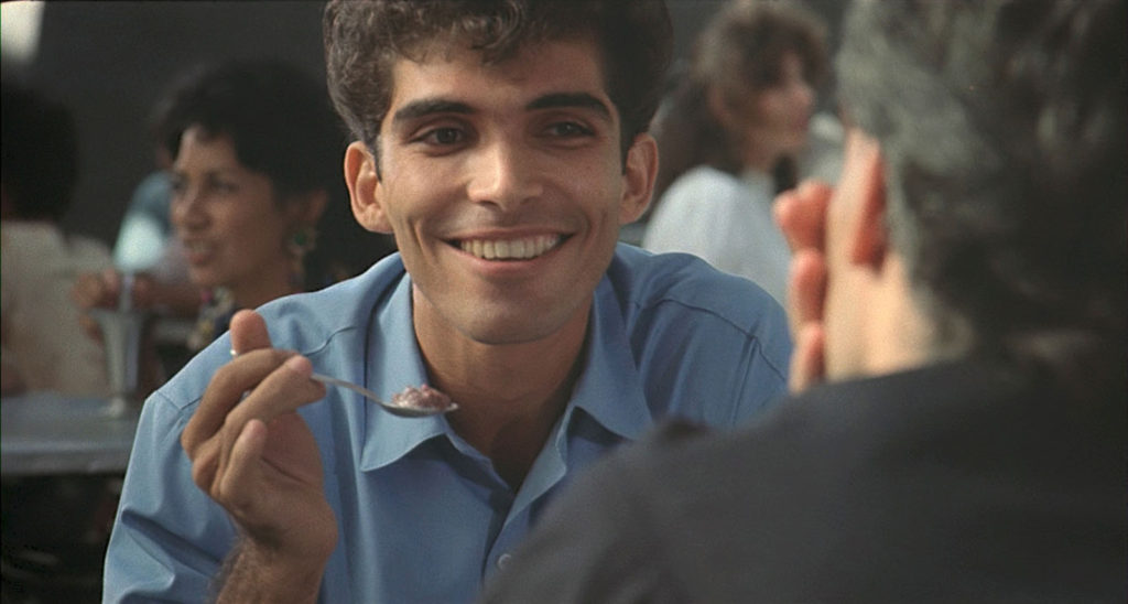 We see David's face and the back of Diego's head. David is smiling at Diego as he holds up a spoonful of ice cream.